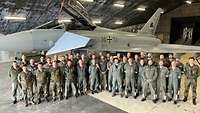 Eine Gruppe von Soldaten posiert vor einem Eurofighter für ein Foto