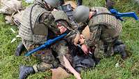 Zwei Soldaten versorgen eine Übungspuppe mit einer schweren Beinverletzung.