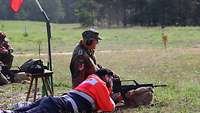 Ein Mann schießt mit einem Gewehr und ein Soldat steht neben ihm