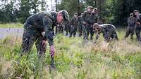 Soldaten, die den Boden mit Sonden nach metallischen Gegenständen absucht