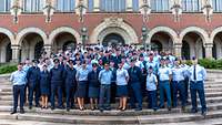 Soldaten in blauen Uniformen stehen auf den Stufen vor einem Backsteingebäude.