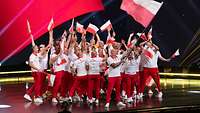 Das polnische Team mit polnischen Fahnen in der Hand steht auf der Bühne