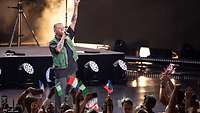 US-Rapper Macklemore steht mit Mikro vor Zuschauern.