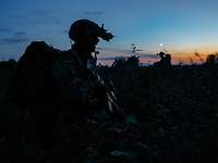 Silhouette eines Soldaten mit Helm, Nachsichtgerät und Rucksack auf dem Rücken in der Abenddämmerung