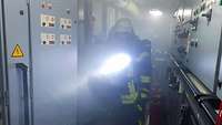 Ein Feuerwehrmann geht im Rauch durch einen engen Gang in einem Schiff