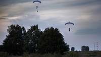 Zwei Fallschirmspringer befinden sich circa 40 Meter über dem Boden noch in der Luft.