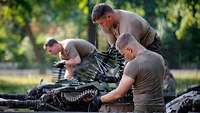 Soldaten arbeiten an den Hauptwaffen von drei Gefechtsfahrzeugen.