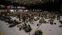 Viele Soldaten sitzen in einer großen Halle.