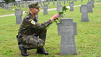 Militärpfarrer Mateusz Szeliga, legt eine Blume am Kreuz nieder
