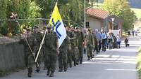 Soldatinnen und Soldaten mit einer Fahne und einem Kreuz auf dem Weg nach Weißenregen