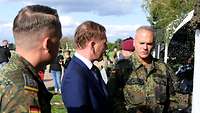 Zwei Soldaten stehen neben dem Ministerpräsidenten und sprechen mit ihm. 