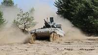 Frontal view of a tank in deep sand in front of a forest