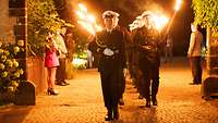 Soldiers holding torches walking past the guests