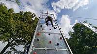 Soldat erklimmt gesichert einen Kletterturm