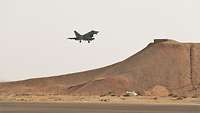 Ein Kampfflugzeug landet vor Wüstenpanorama