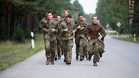 Eine Gruppe von Soldaten rennen auf einer asphaltierten Straße.