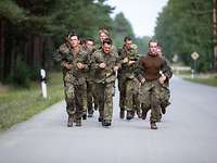 Eine Gruppe von Soldaten rennen auf einer asphaltierten Straße.