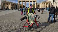 Ein Radfahrer mit seinem Rennrad präsentiert ein Sportshirt der Bundeswehr vor dem Brandenburger Tor