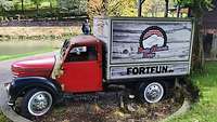 Ein roter Oldtimer-LKw auf dem FortFun auf der Ladefläche steht. 