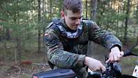 Ein Soldat im Wald entfernt die Spiegel seines Motorrads.