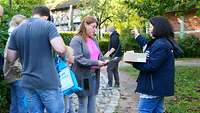 Eine Frau übergibt einer Familie mit Kindern einen Geländeplan.