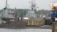 The surfaced U17 submarine passes naval ships in a port.