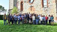 Eine Personengruppe vor einer Kirchenruine. 