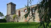 Eine alte Kirchenruine steht auf einer Wiese.