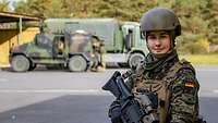 Soldatin mit Gewehr vor Bundeswehr-Fahrzeug
