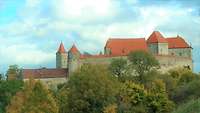 Die Burg Harburg auf einem bewaldeten Hügel unter einem bewölkten Himmel