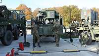 Zwei Soldaten legen den Tankschlauch zurück auf ihr Tankfahrzeug. 