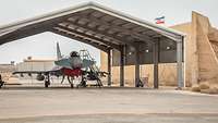 Ein Eurofighter steht in einem Shelter. Daneben weht auf einem Hügel die Fahne Mecklenburg-Vorpommerns.