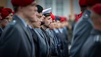 Frauen und Männer in Uniform stehen in Reih und Glied vor einem Schloss.