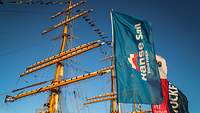 Ein Segelmast des Segelschulschiffes mit einer Flagge mit dem Logo der Hanse Sail Rostock.