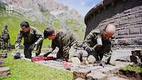 Soldaten arbeiten mit Werkzeugen an einem Steinweg.