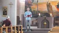 Ein Mann steht vor einem Altar einer Kirche und hält eine Predigt.
