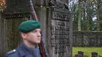 Ein Soldat steht vor einem Gedenkstein auf dem Jüdischen Friedhof Berlin