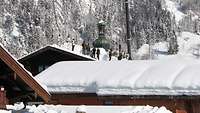 Mehrere Soldaten schaufeln den Schnee von einem Dach. Sie sind umgeben von Schneemassen.