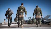 Drei Soldaten laufen über ein Rollfeld