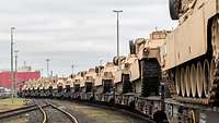 Mehrere Panzer stehen auf Eisenbahnwaggons