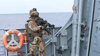 Zwei Soldaten sichern mit Waffen in der Hand die Situation an Bord eines Schiffes.