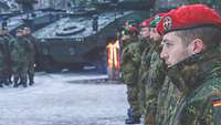Zahlreiche Soldaten stehen auf einem Platz in Formation, im Vordergrund ein Soldat mit rotem Barett