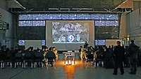 A room full of people, sitting and following a briefing lecture by the weapons instructor course.