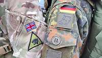 Zwei uniformierte aneinander lehnende Ärmelpartien mit deutscher und britischer Flagge