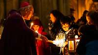 Bischof Rudolf übernimmt von einem Kind das Friedenslicht