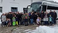 Mehrere Menschen stehen für ein Gruppenbild vor einem Bus. 