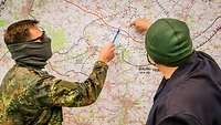 Ein Soldat zeigt mit einem Stift auf einer Lagekarte einem anderen Mann einen Standort