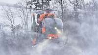 Ein Hubschrauber wirbelt beim Abheben feinen Schneestaub durch die Luft und verdeckt sich damit selbst