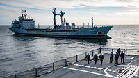 Mehrere Soldaten stehen auf dem Oberdeck eines Schiffes. Ein weiteres Schiff steht dem gegenüber.