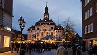 Das beleuchtete Lüneburger Rathaus lässt den davor liegenden Weihnachtsmarkt malerisch erscheinen.